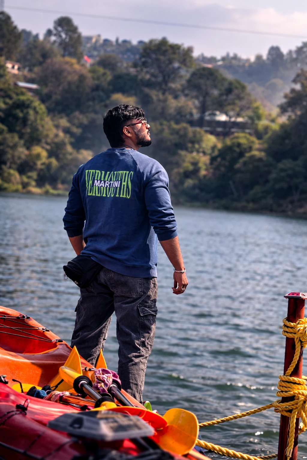 Mahendra Chiravande standing near kayaks at a lakeside travel location